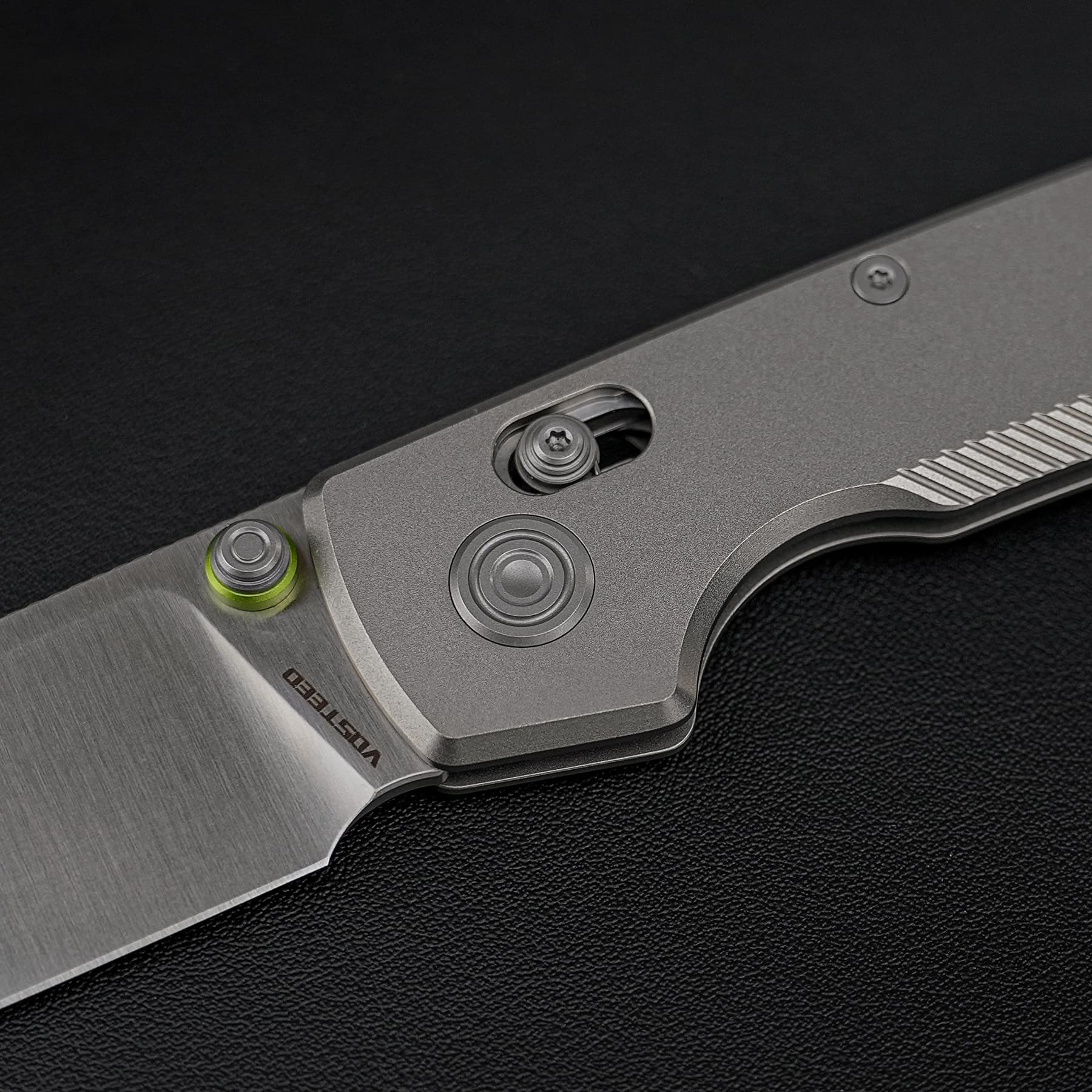 Close-up of a silver utility knife handle with exposed blade and screws on a dark textured surface.