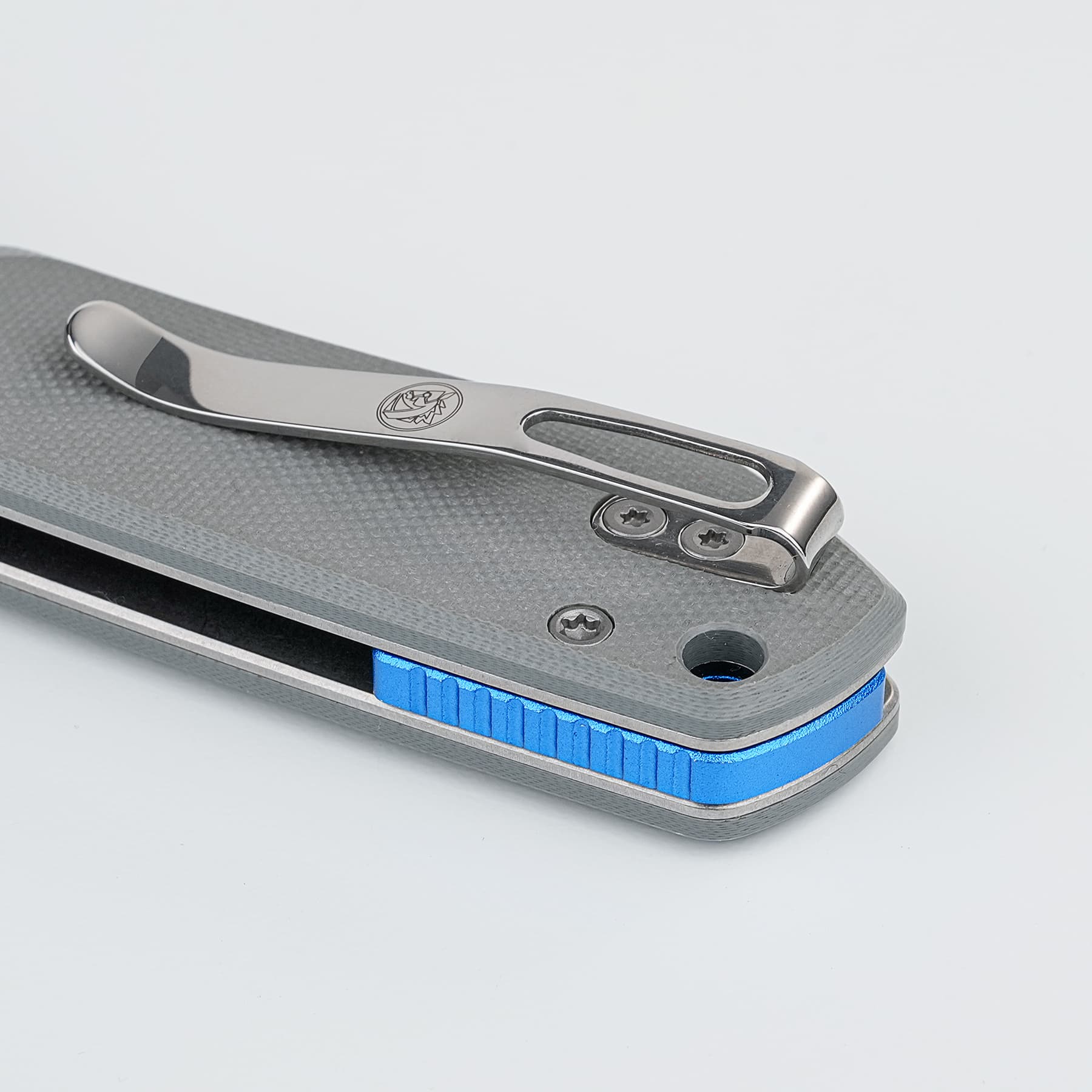 Close-up of a metal stapler with a blue base on a textured gray surface, showing screws and a brand logo.