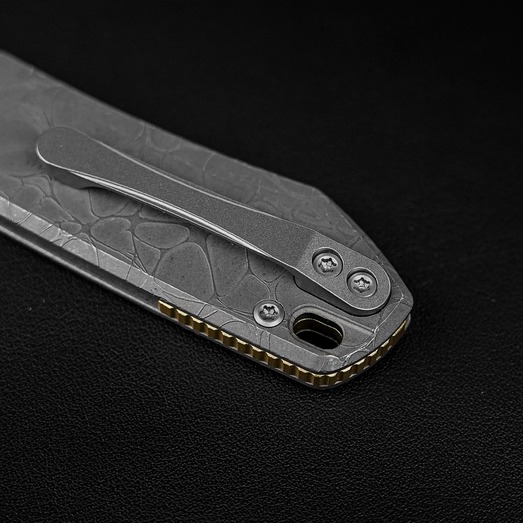 Close-up of a gray folding knife with a textured handle and partially exposed blade on a black background.