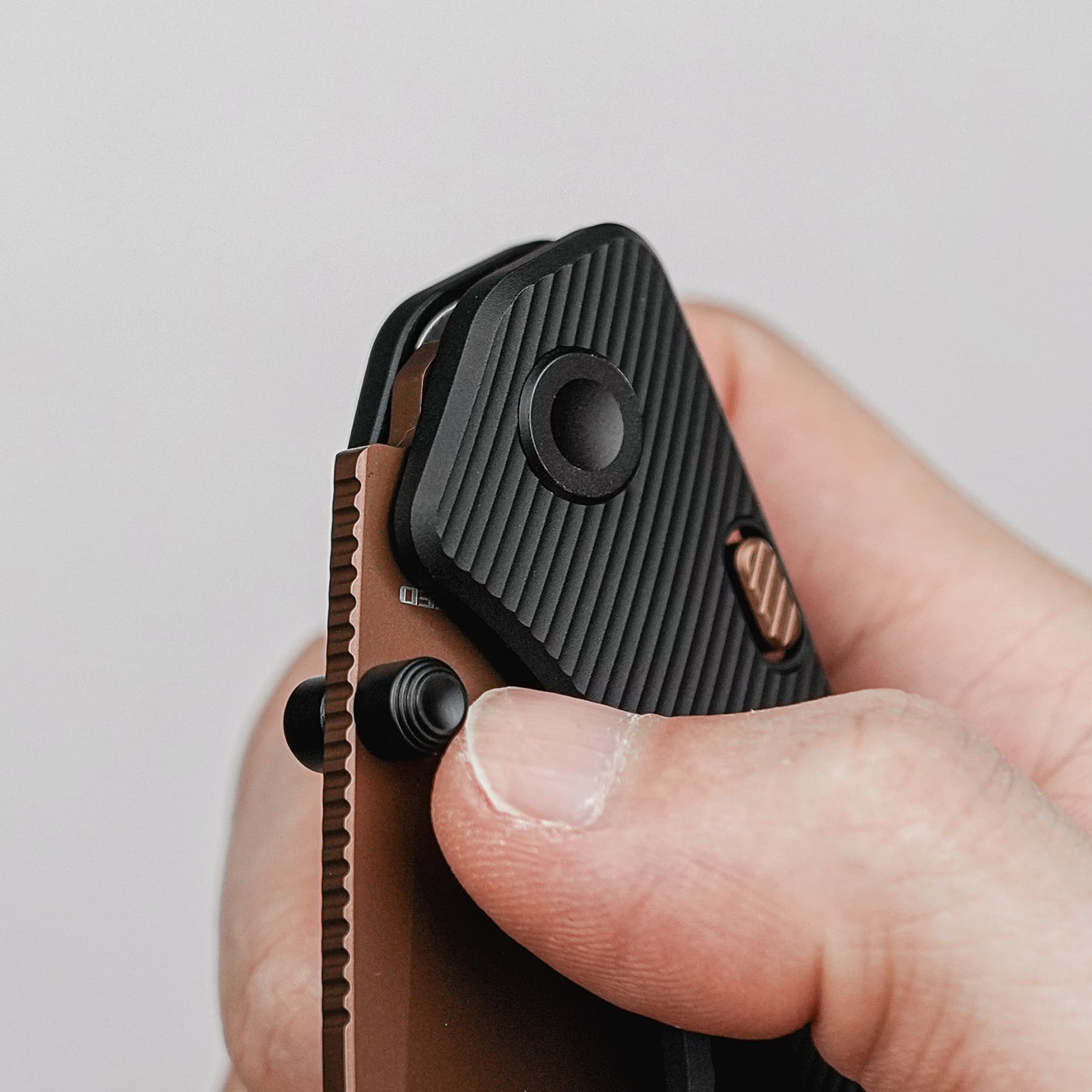 Close-up of a hand holding a small black ribbed device with a circular dial and copper accents.