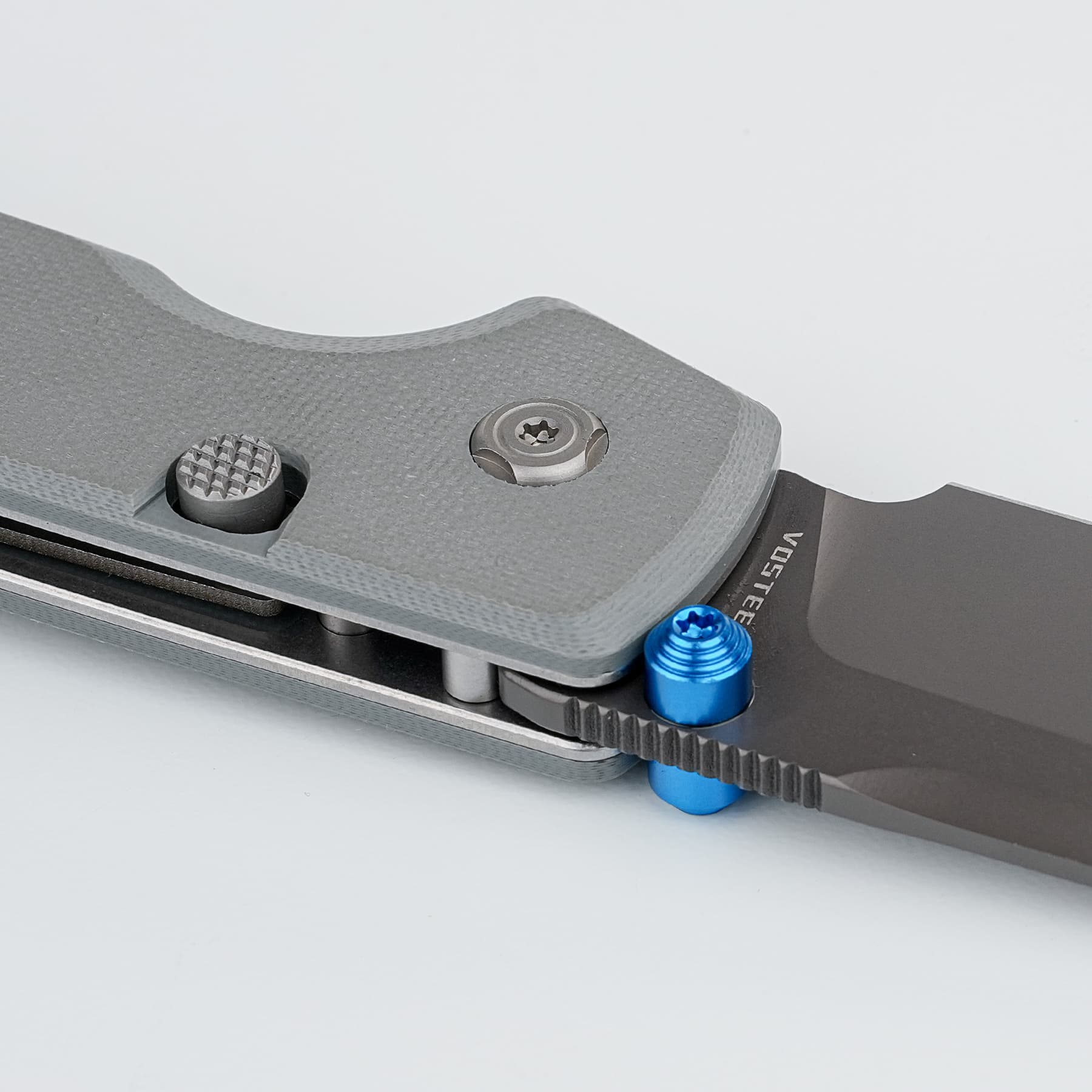 Close-up of a gray metal clamp with a knurled textured knob and blue fasteners, showing screws and a ridged belt/rail component in the foreground.