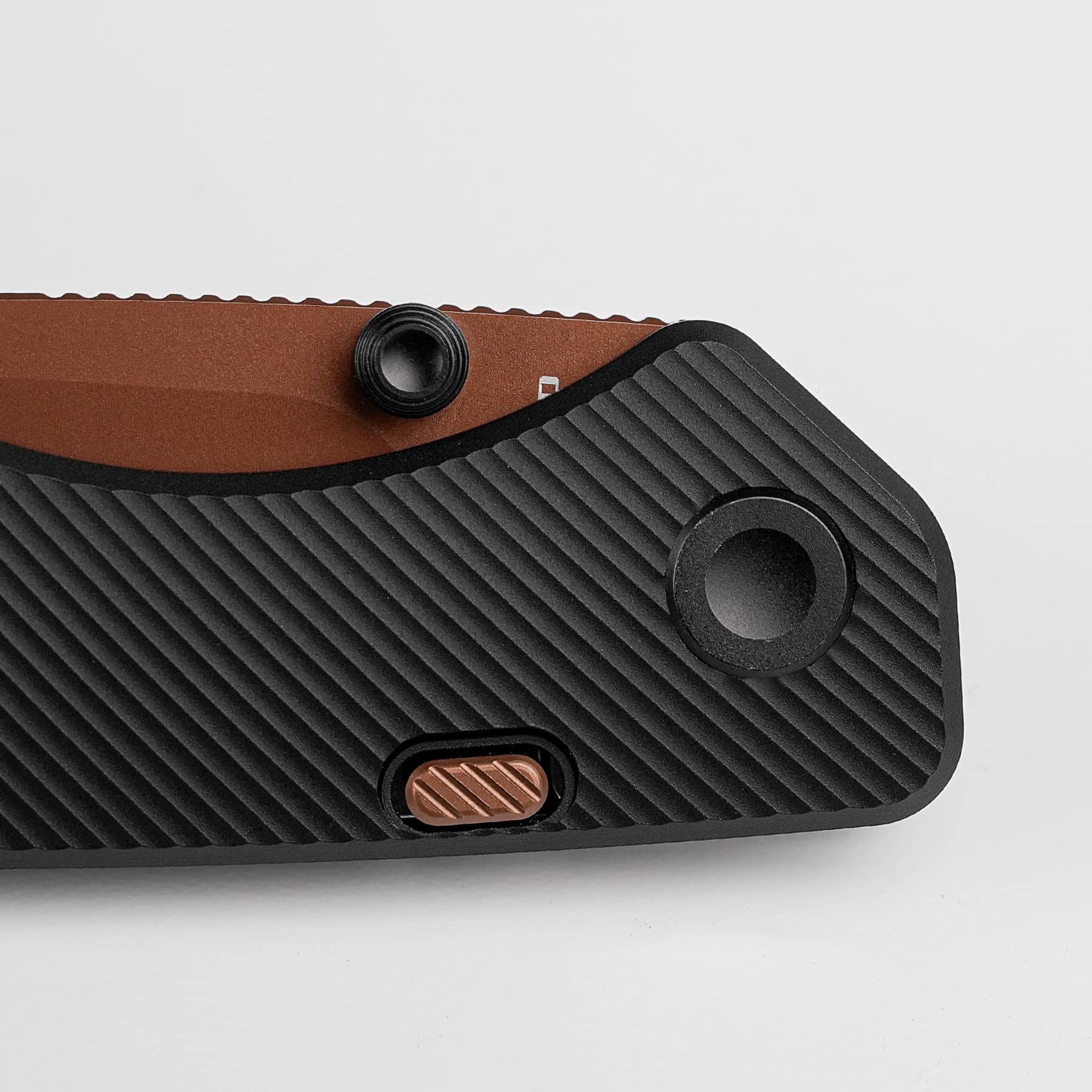 Close-up of a textured black surface with a brown stripe, featuring a small black round knob and a copper rectangular switch.