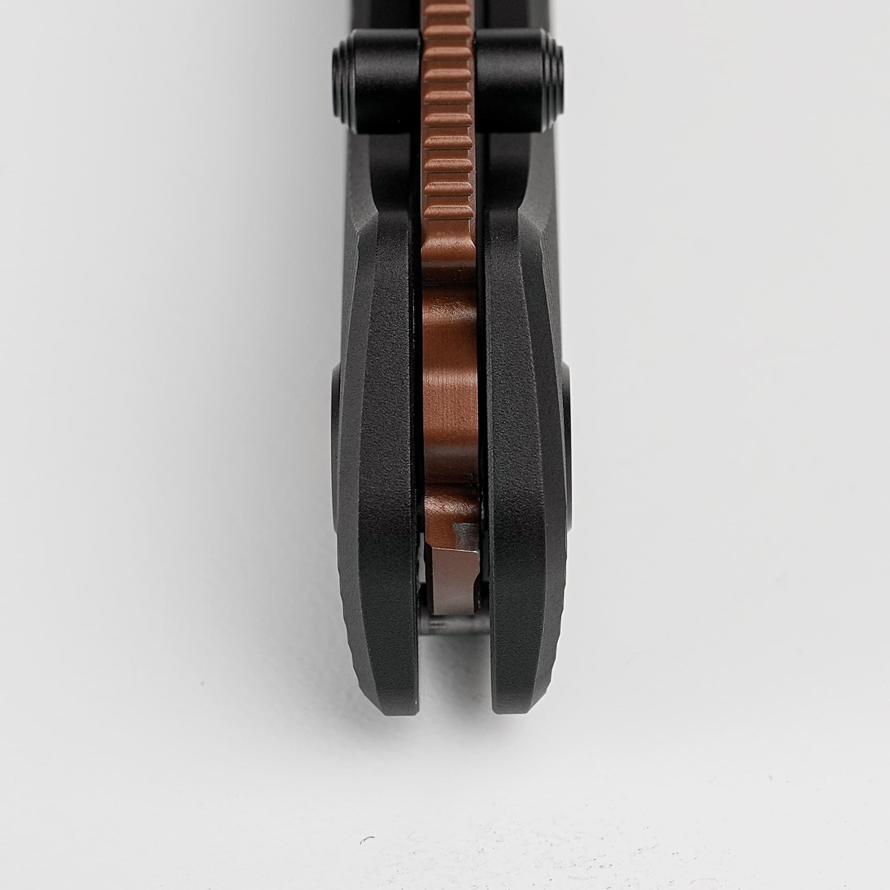 Close-up of a brown toothed gear between dark black metal components, viewed from above.