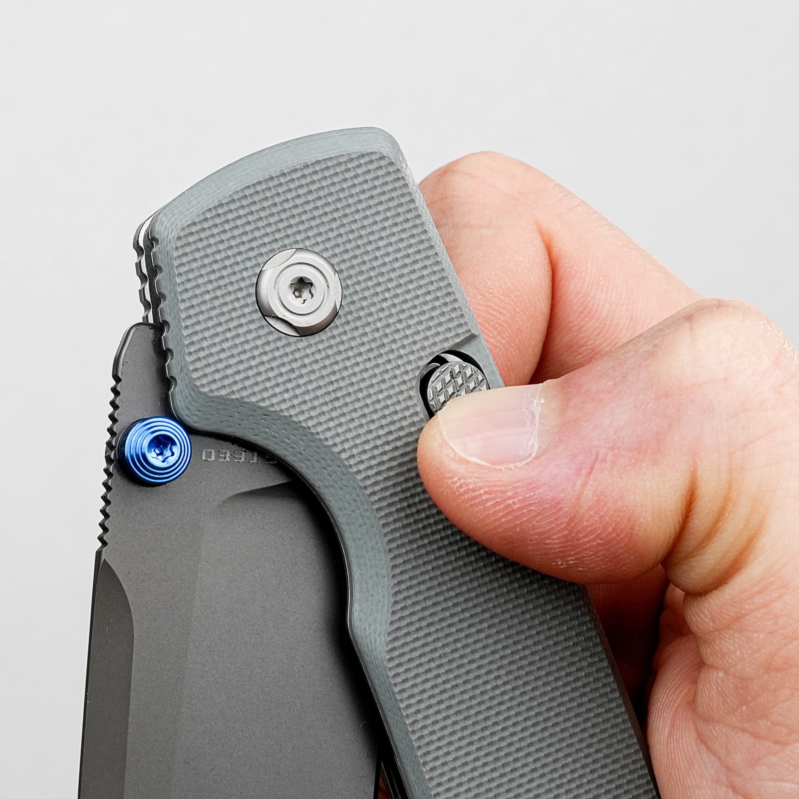 Close-up of a hand gripping a gray folding utility knife with a textured grip and visible blade area.