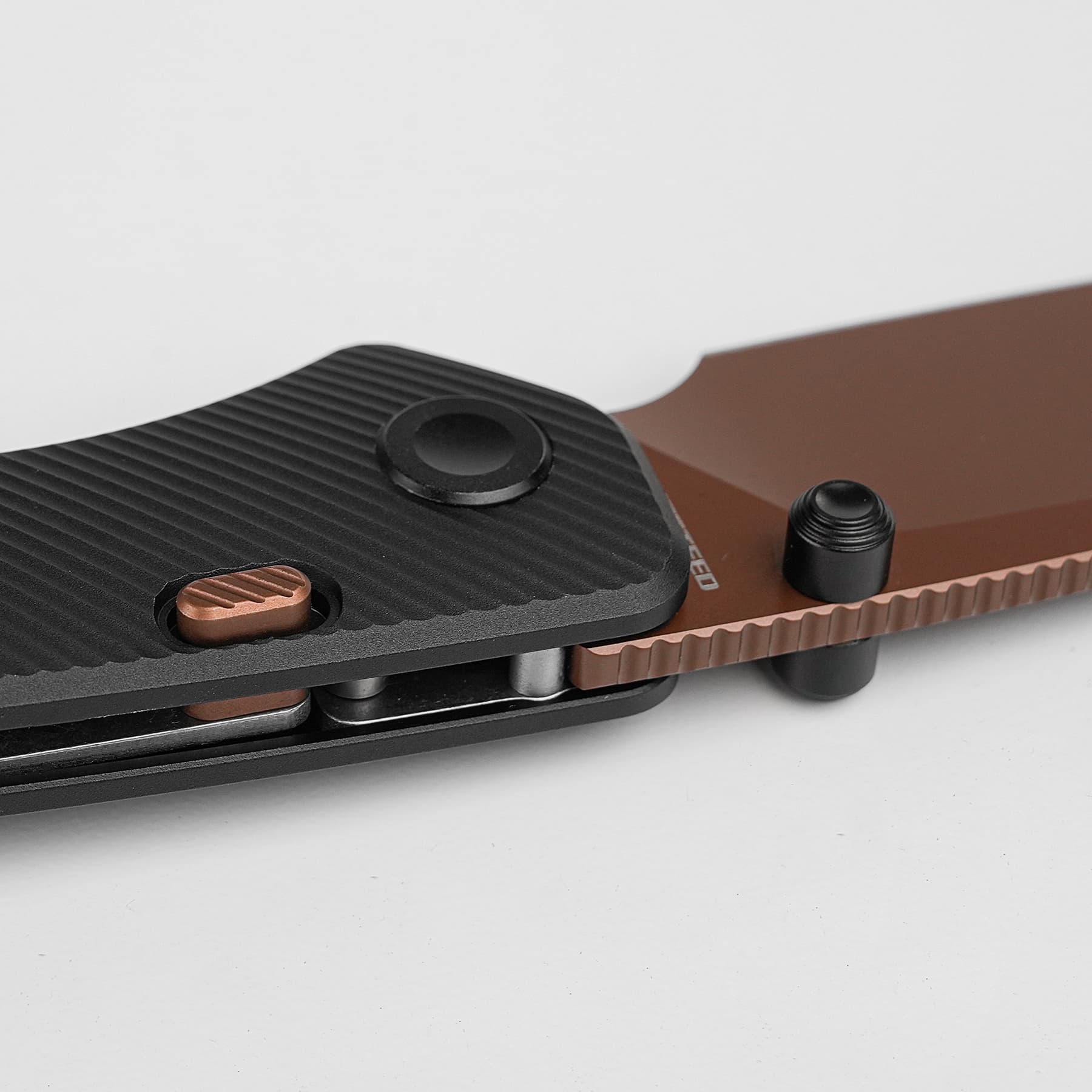 Close-up of a camera tripod quick-release plate with a textured black surface, copper screw, and brown mounting base.