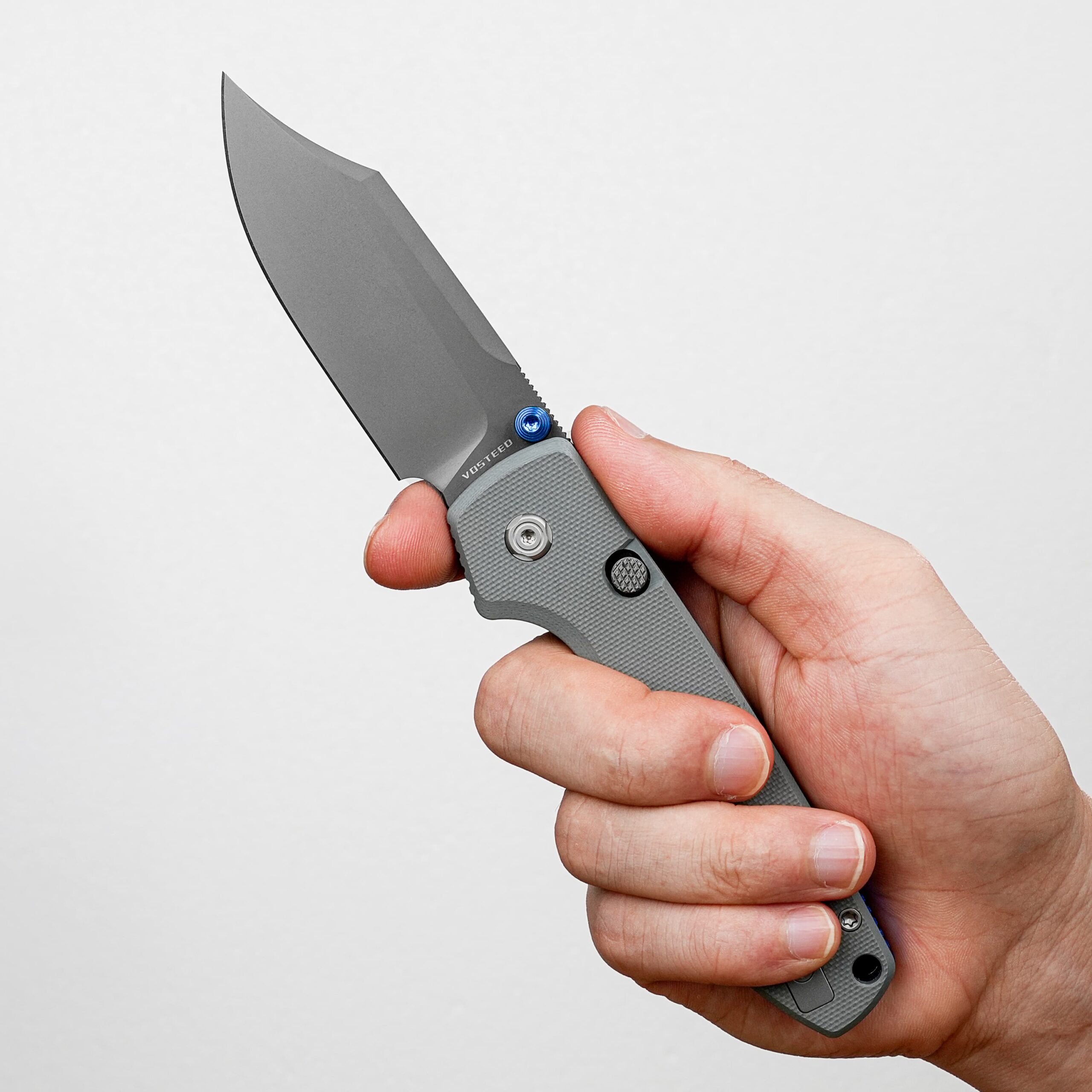 Close-up of a hand gripping a gray folding knife with the blade partially extended.