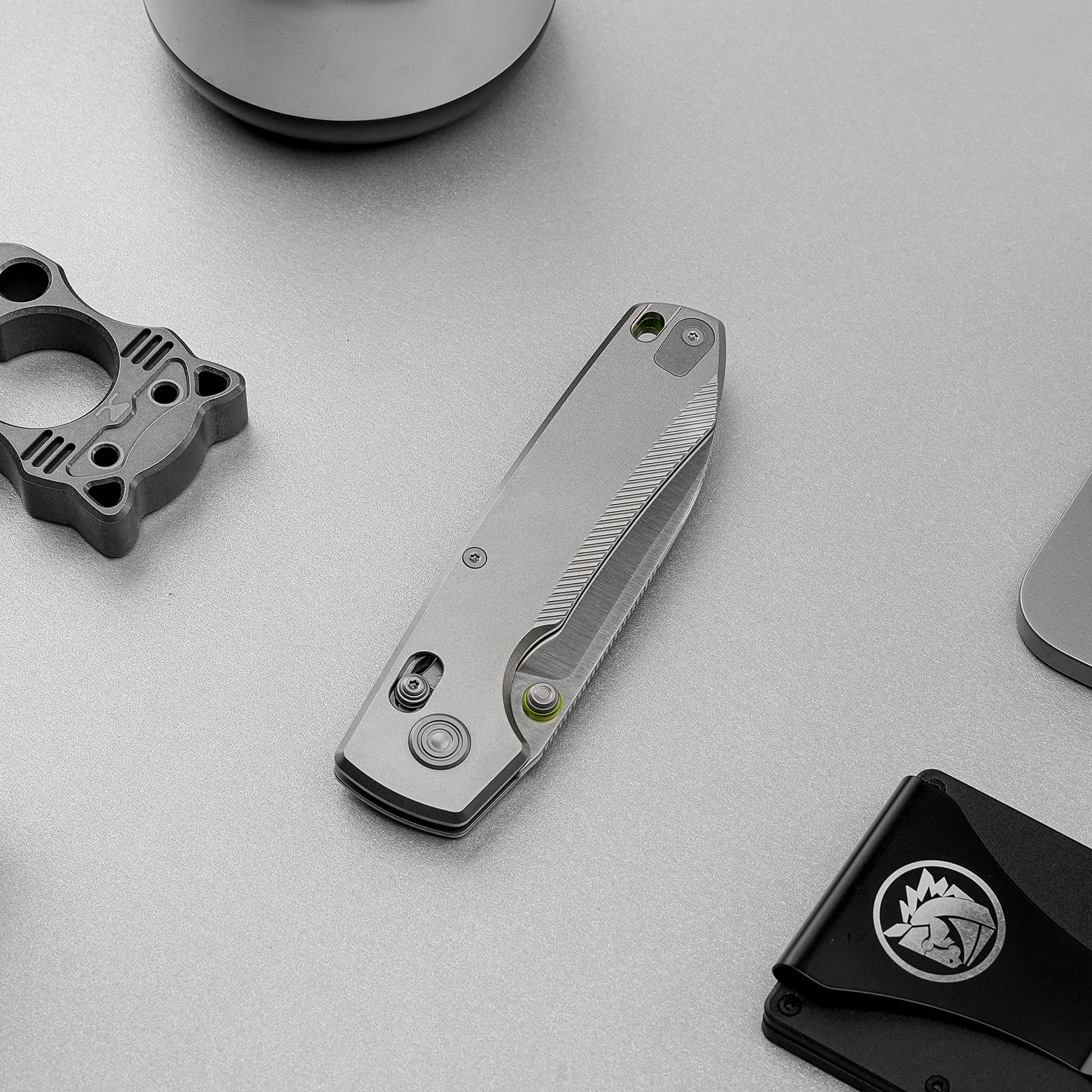 Close-up of a metallic multitool with a built-in bubble level on a gray surface, alongside other tools.