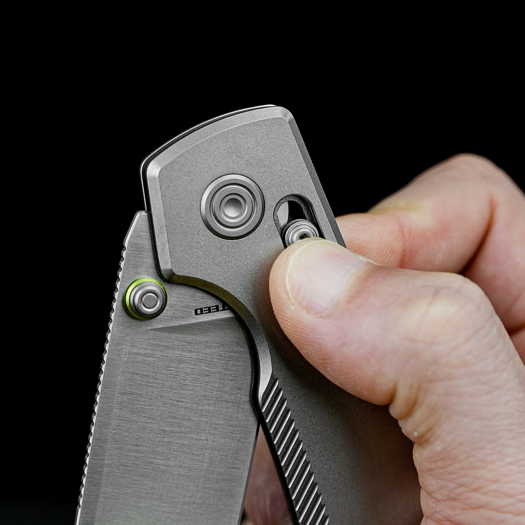 Close-up of a hand holding a locking utility knife with a sharp blade exposed against a black background
