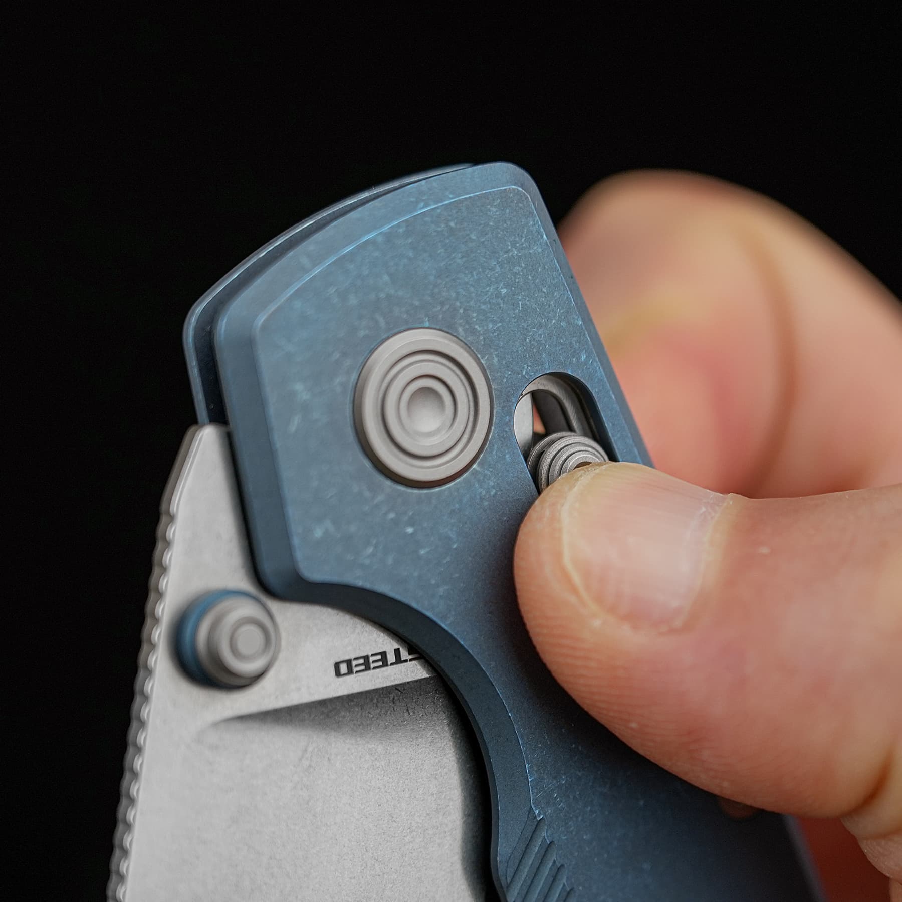 Close-up of a blue utility knife being opened, thumb sliding the blade out from the handle