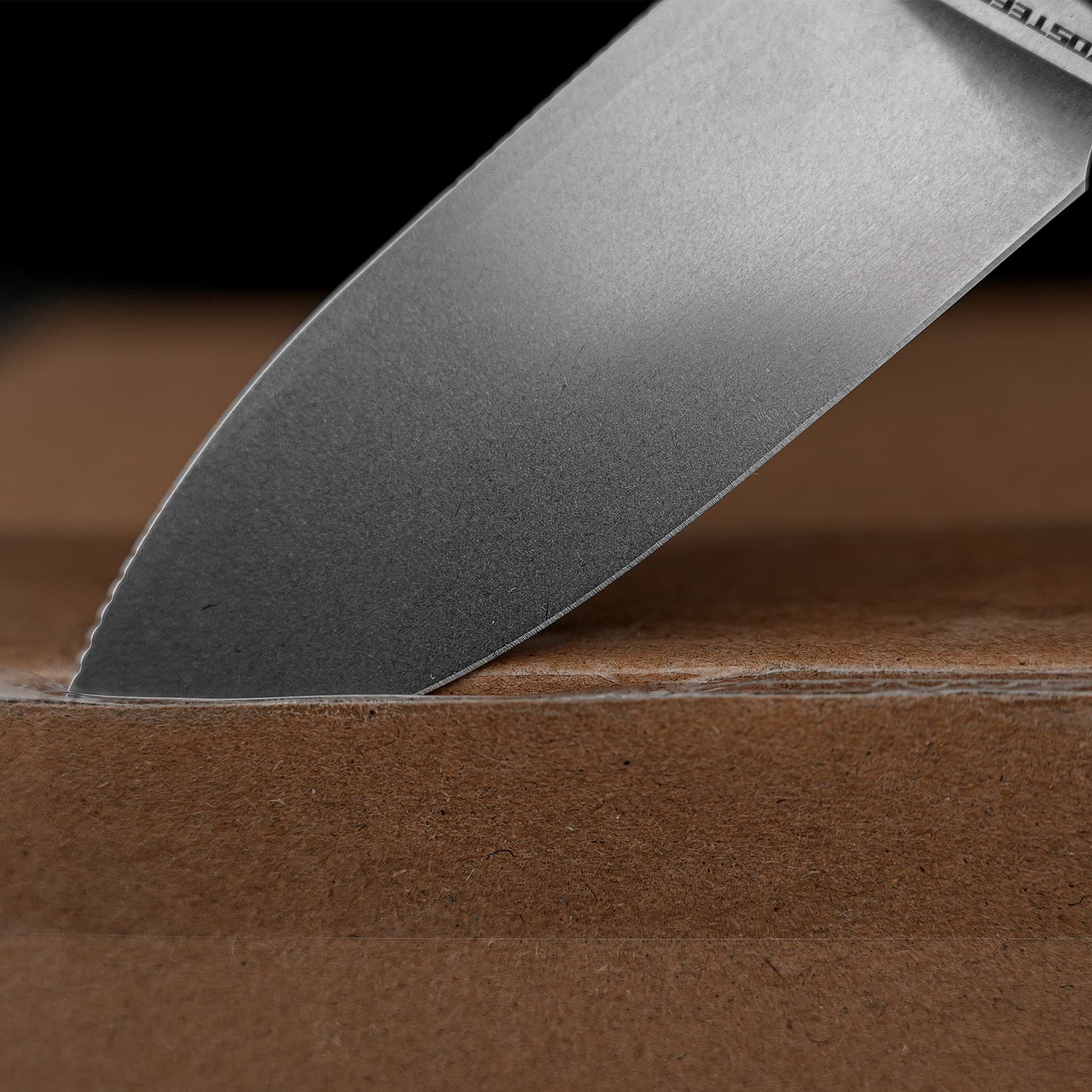 Close-up of a sharp knife blade pressing into a loaf on a wooden cutting board.
