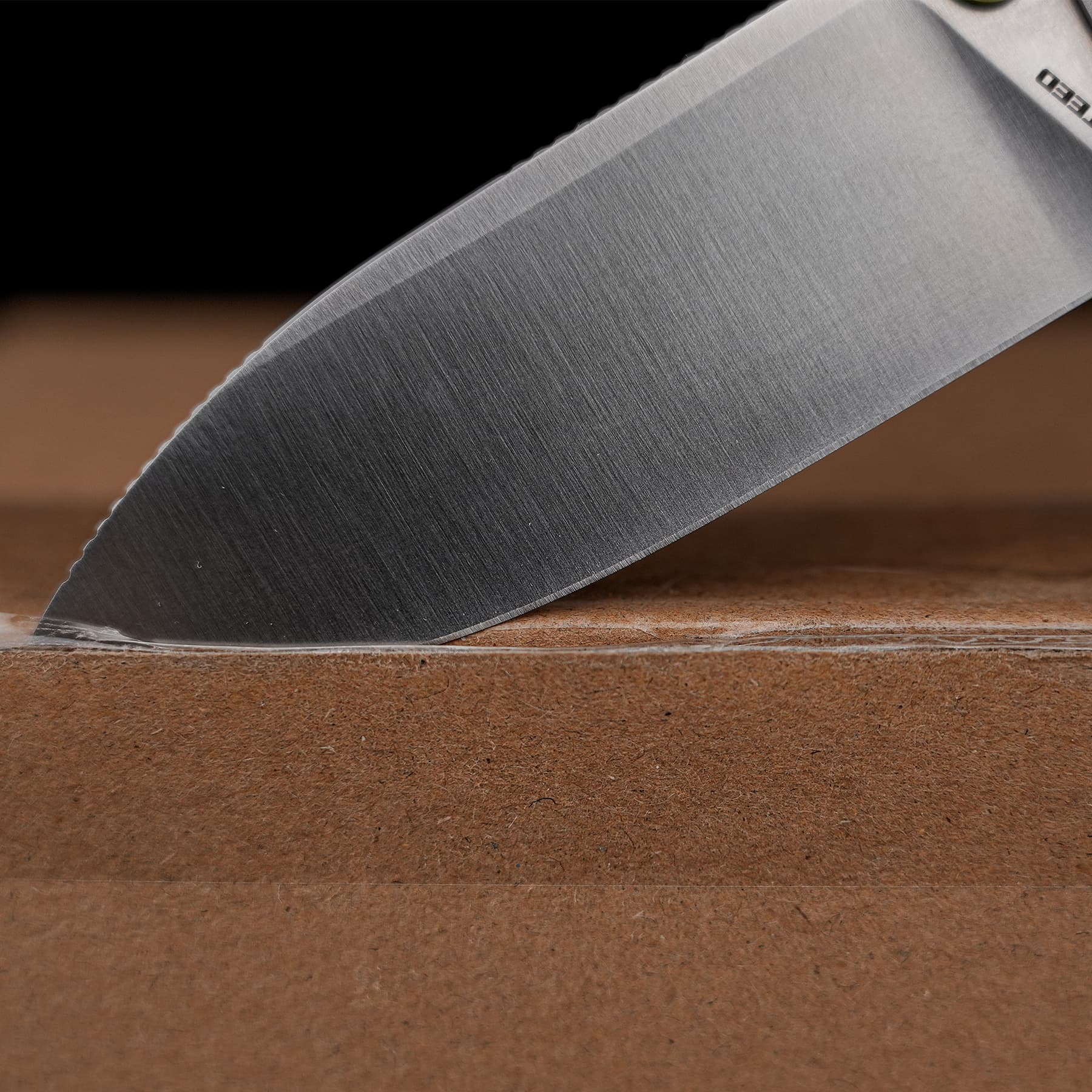 Close-up of a sharp steel kitchen knife blade resting on a brown wooden cutting board.