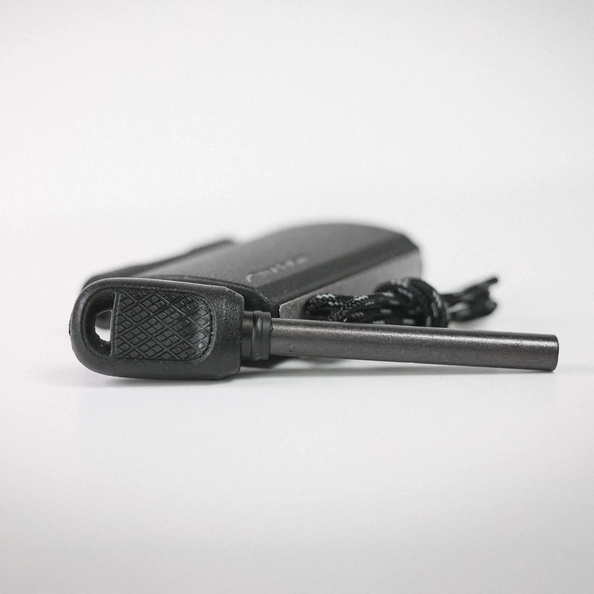 Close-up of a black camera body with textured grip resting on a light surface, cropped to show the front edge.